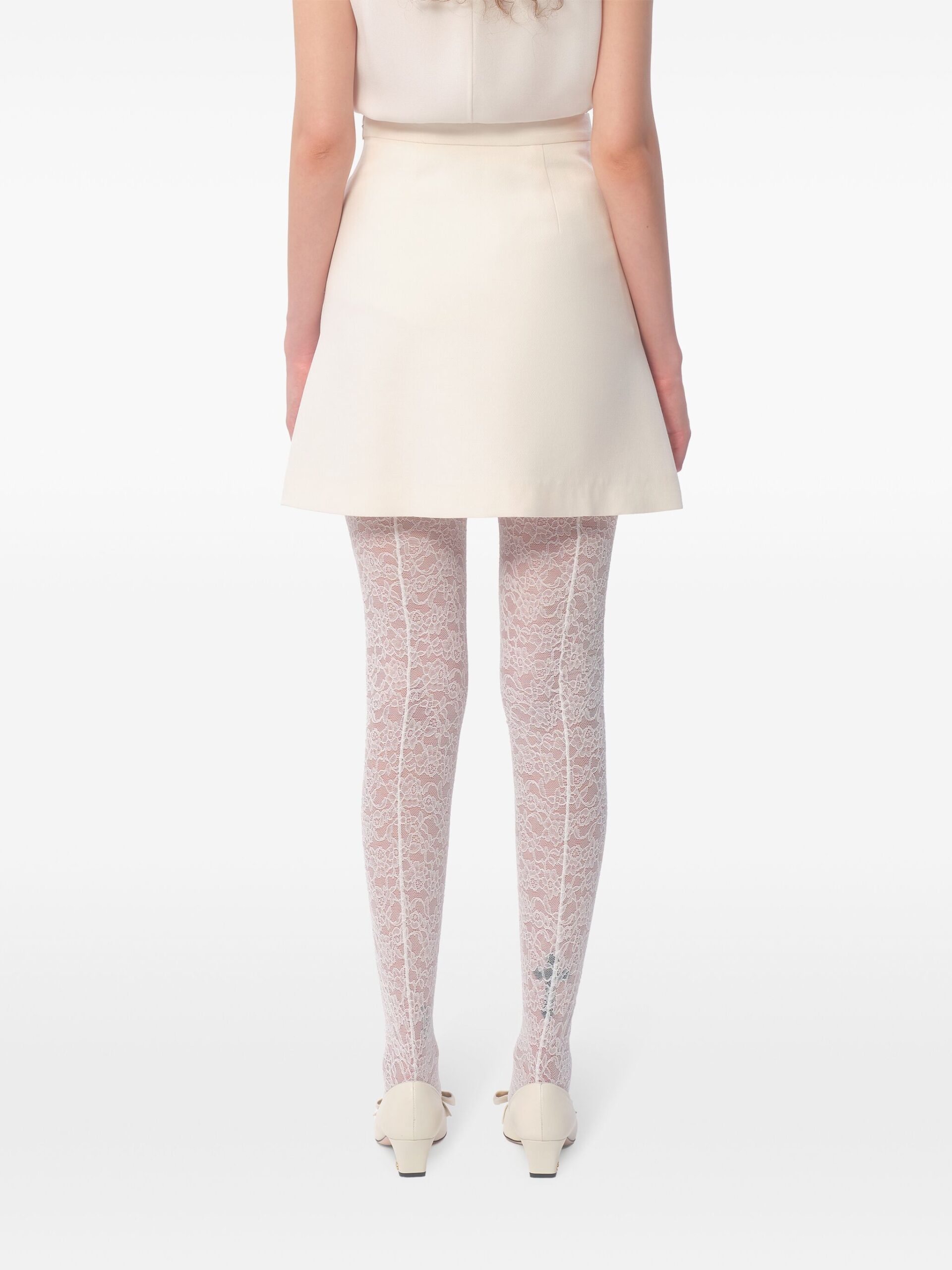 Capa de mulher elegante com saia branca e collants de renda rosa claro, sapatos de salto baixos.