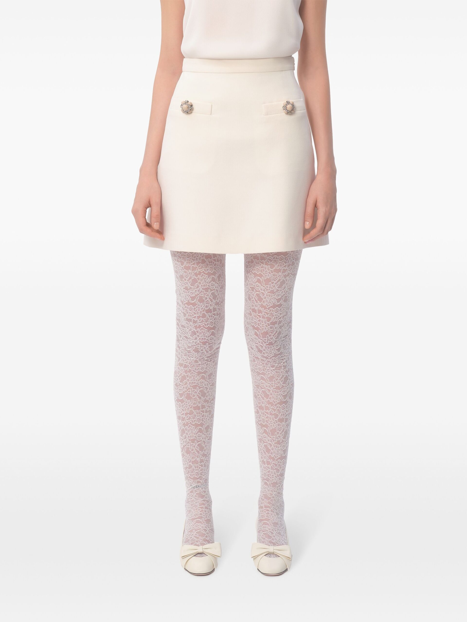 Blusa branca elegante e saia lápis bege, detalhes de botões e laços em sapatos de looks femininos sofisticados.