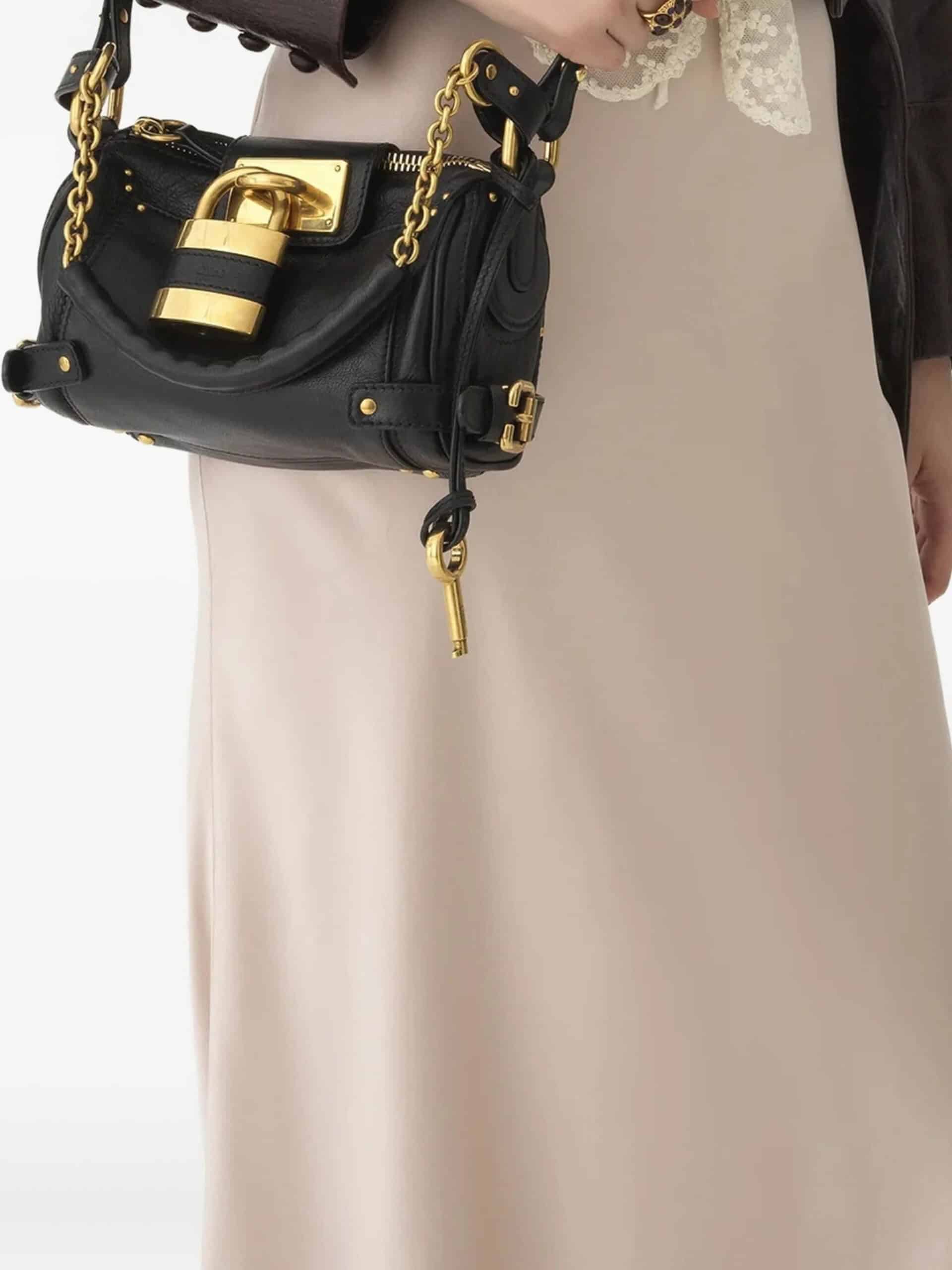Bolsa de couro preta com fecho dourado e cadeado, estilo elegante e sofisticado.